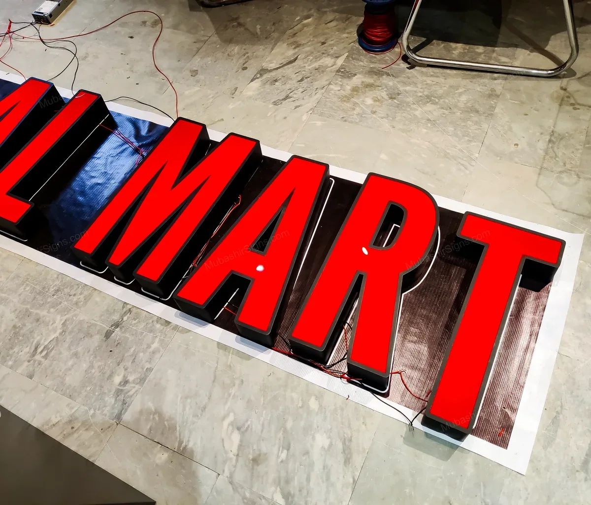 Letras rojas independientes de 786 Halal Mart colocadas sobre una plantilla impresa en el taller